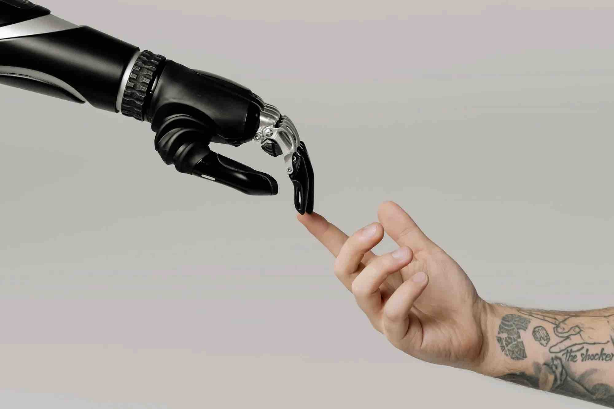 Robotic hand and human hand reaching each other.